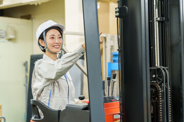 フォークリフトに乗って安全確認をする女性作業員 © taka
