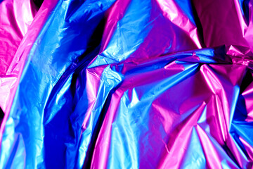 Crumpled foil in neon light as background