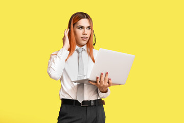 Beautiful transgender secretary in headset with laptop on yellow background