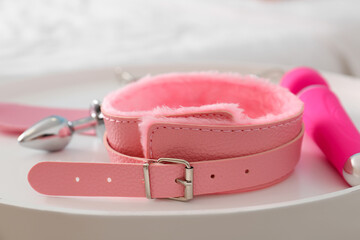 Pink collar with sex toys on table in bedroom, closeup