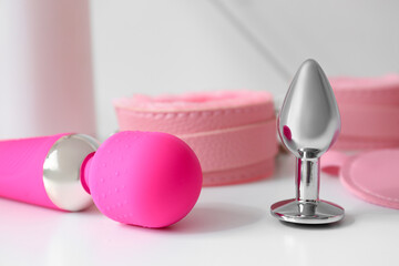 Pink sex toys on shelf near light wall, closeup