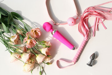 Sex toys with roses on white table, top view