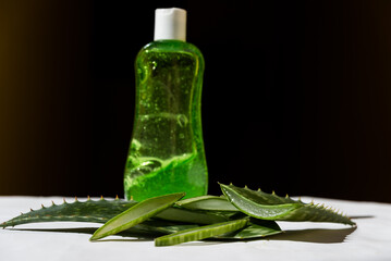 pieces of Aloe Vera leaves on a table next to a plastic bottle with its juice