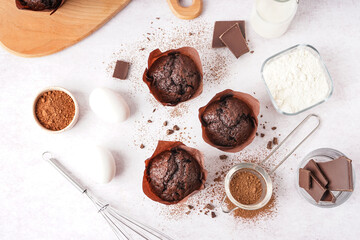Composition with tasty chocolate muffins and ingredients on light background