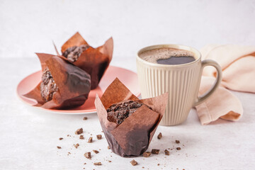 Sweet chocolate muffins and cup of coffee on light background