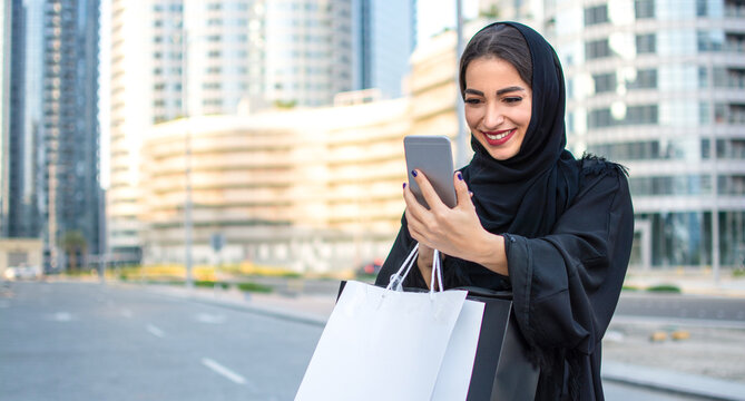 Young beautiful Arabian middle eastern woman talking on video call with smartphone on the city street. Muslim woman using mobile phone.