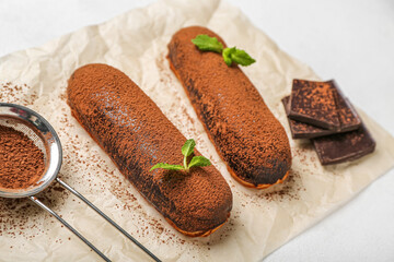 Baking paper with tasty chocolate eclairs on table, closeup