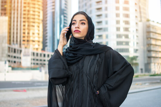 Beautiful Arab businesswoman wearing Abaya talking on smart phone on the street.