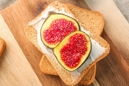 Wooden board of delicious bruschettas with cream cheese and figs, closeup