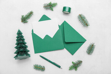 Envelopes with blank card, fir branches, Christmas tree candle and pen on white background