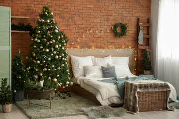Fototapeta na wymiar Interior of bedroom with Christmas wreath, fir trees and glowing lights