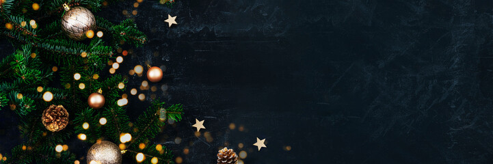 Obraz na płótnie Canvas Banner with Christmas tree branches, golden baubles and pine cones on black background with Christmas bokeh lights. New Year concept. Top view, copy space