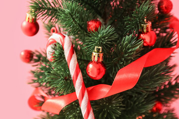 Small Christmas tree with decor near red wall, closeup