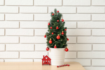 Small Christmas tree with toys on table near white brick wall