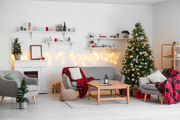 Interior of living room with glowing Christmas trees, fireplace and sofa
