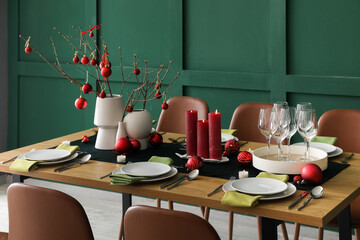 Vases with tree branches and red Christmas balls on dining table in room