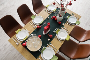 Vases with tree branches and red Christmas balls on dining table in room