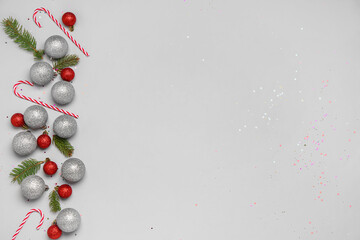 Christmas balls with fir branches and candy canes on grey background