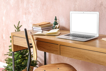 Workplace with laptop and Christmas decor near pink wall