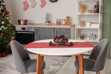 Dining table with fir cones in kitchen decorated for Christmas