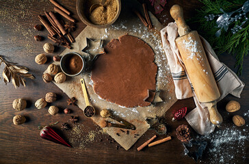 An arrangement of gingerbread pastry, natural ingredients and baking utensils on an old wooden table. Christmas baking. Top view