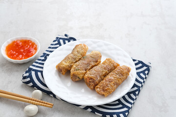Lumpia Kulit Tahu, chicken shrimp spring rolls wrapped in tofu skin. Served with sauce.
