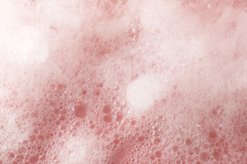 Fototapeta premium Fluffy bath foam on pink background, closeup