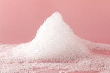 Fluffy bath foam on pink background, closeup. Care product