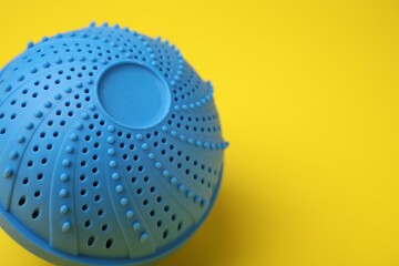 Laundry dryer ball on yellow background, closeup. Space for text
