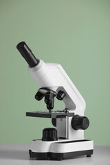 Modern microscope on table against green background