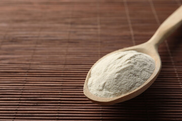 Spoon of agar-agar powder on bamboo mat, closeup. Space for text