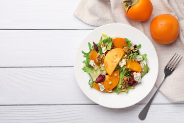 Delicious persimmon salad and fork on white wooden table, flat lay. Space for text