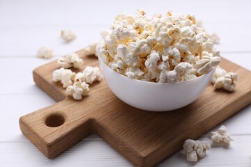 Tasty popcorn in bowl on white wooden table