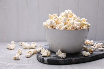 Bowl of tasty popcorn on grey table, space for text