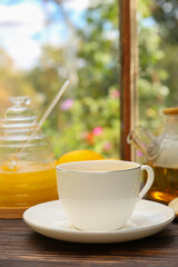 Cup of delicious tea with lemon and honey on wooden table