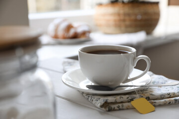 Tea bag in cup on white wooden table indoors. Space for text