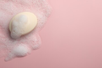 Soap with fluffy foam on pink background, top view. Space for text