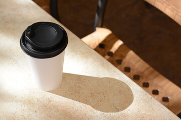 Takeaway coffee cup on beige table in cafe, space for text