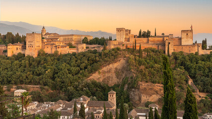 Fototapeta na wymiar Sunset photo of the Alhambra fortress in Granada, Spain. The fortress is bathed in a golden, reddish glow.
