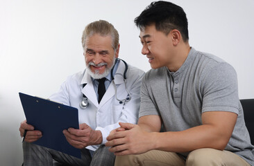 Senior doctor with clipboard consulting patient in clinic
