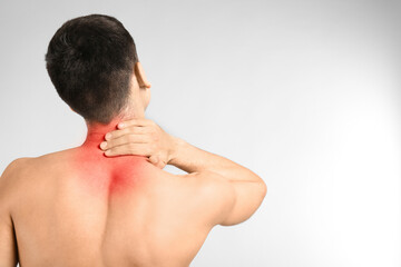 Obraz premium Young man suffering from neck pain on light background