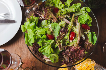 Fresh vegetable salad with tomato, spinach, micro greens, cheese on wooden table background. Healthy food, clean eating gluten free bowl salad top view. Caesar salad with a glass of wine for dinner.
