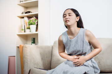 woman having stomachache on sofa