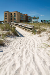 Path on sand heading to a boardwalk in the middle of sand dunes at the front of hotel- Destin, FL