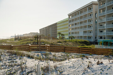 Fototapeta na wymiar Hotel buildings with wood pathways on a white sand dunes outdoors in Destin, Florida