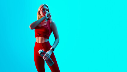 Young attractive sports girl in red sportswear on bright neon cyan background
