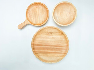 Flat lay of the empty wooden plate, wooden bowl, and wooden plate with a handle on white background.