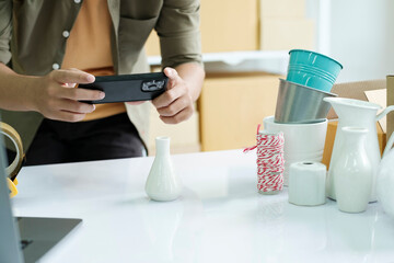 Young male online business owner using cellphone checking parcel box.