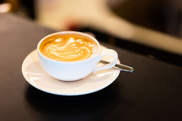 A cup of hot latte on the table in the cafe.