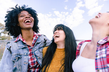 Fototapeta premium Haitian woman laughing with her two Latina friends in a park
